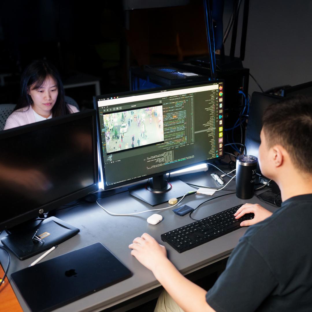 Two people working at computer stations in a lab